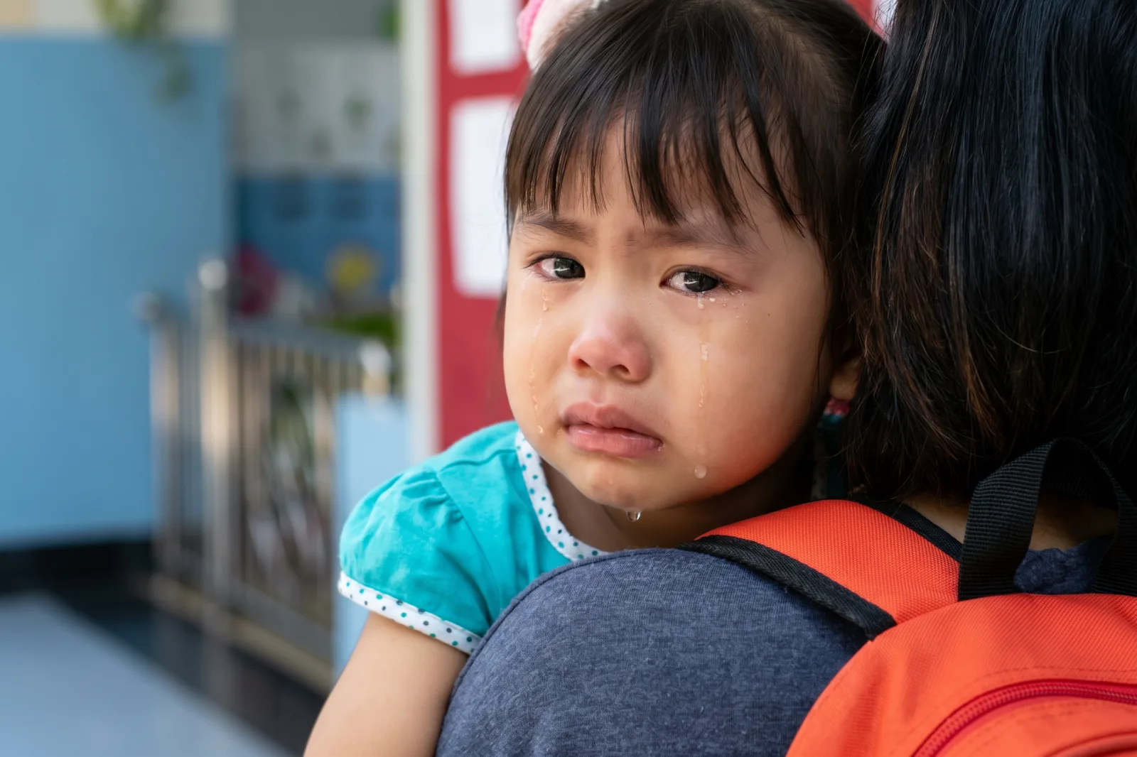 孩子依偎在大人肩上，脸颊上挂着泪珠。