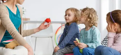 Teacher showing a group of young children a small toy